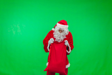 Santa Claus getting presents out of his bag on green background