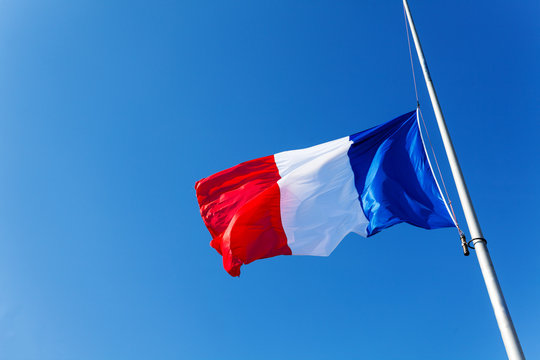 Lowered to half-staff flag of France over blue sky