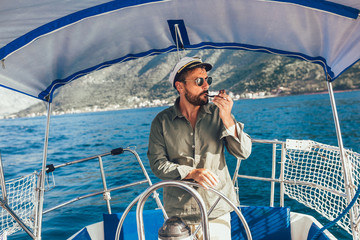Handsome man on a sailing boat smokes a pipe