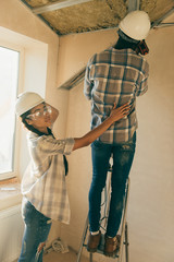 beautiful young woman supporting her husband while he making renovation of home
