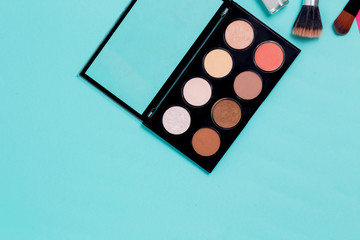 Horizontal blue paper background for text with makeup. Multi colored palette of shadows
