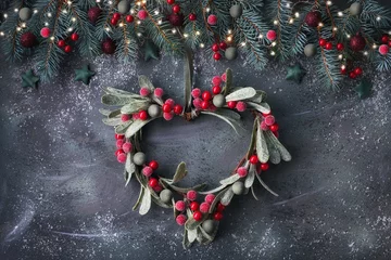 Foto auf Acrylglas Heart-shaped mistletoe Christmas wreath and festive garland made from fir twigs, frosted berries and trinkets © tilialucida