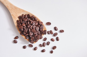 Obraz premium Coffee beans with wood spoon on the white floor.