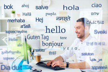 translation, business, and technology concept - smiling male translator or businessman typing on...