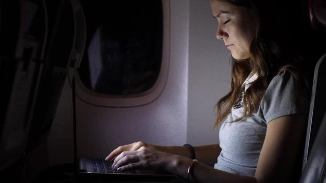 Focused woman work on computer in airliner at night
