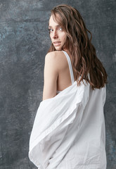 Fototapeta na wymiar Fashion shot of beautiful brunette woman posing in white shirt, top and pants. Studio, grey background