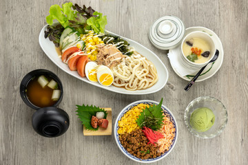 Top view of japanese foods set, fried rice with udon ramen with egg and tuna salad, soup and ice scream over the wooden table, luxury japanese food concept