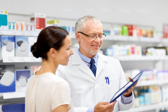 medicine, healthcare and technology concept - senior apothecary and female customer with tablet pc computer at pharmacy