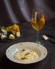 risotto with mussels (seafood rice) in a white plate and a glass of white wine on a dark background