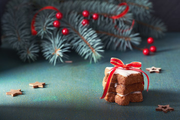 Stack of Christmas star cookies tied up pith red ribbon on green and red festive background with green fir twigs