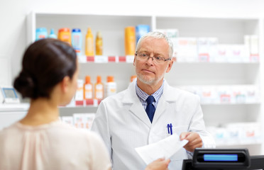 medicine, healthcare and people concept - senior apothecary taking prescription from customer at drugstore