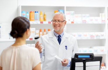 medicine, pharmaceutics, healthcare and people concept - senior apothecary with drug and prescription and female customer at pharmacy