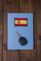 Concept - buying a car in Spain. Key and the Spain flag, against the background of a notepad.