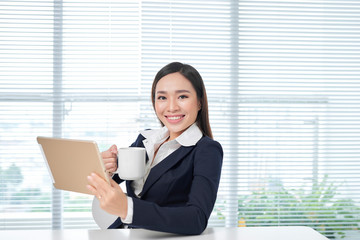 Smiling asian businesswoman sitting in bright office