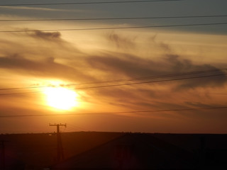 Southern sunset above steppe with power lines.