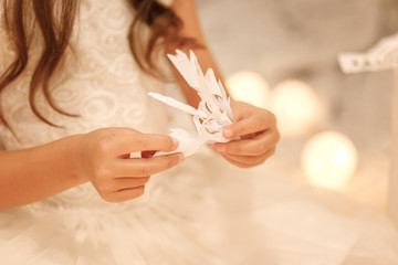 child girl makes paper snowflakes for decoration Christmas tree