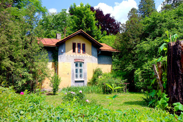 Fototapeta na wymiar Gardener's house in the park among green grass and trees