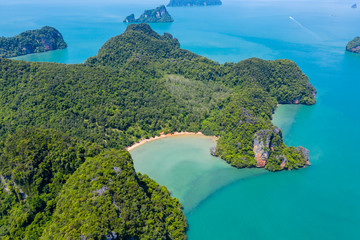 Aerial drone view of a beautiful, isolated tropical sandy beach surrounded by dense, mountainous...
