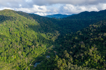 Obraz premium Aerial drone view of mountainous tropical rainforest and a small lake in Thailand