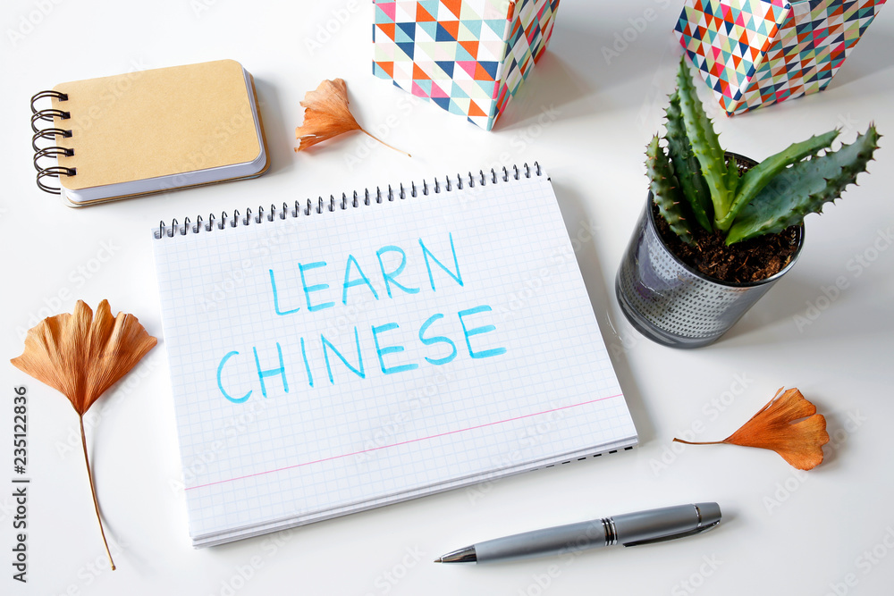 Aufkleber learn chinese written in a notebook on white table