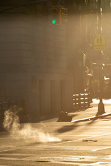Beautiful sunrise in the streets of Manhattan with a manhole that expels steam, New York, United States.