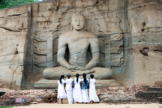 Five religious women are standing and admiring the great Samadhi Statue in Polonnaruwa, Sri Lanka.