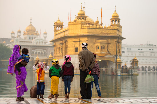 An indian family is admiring the majestic Golden Temple of Amritsar in the state of Punjab, India.