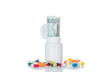 close up shot of pill bottle with russian cash money surrounded by colorful different pills isolated on white