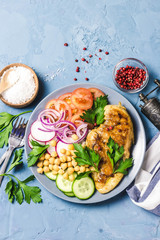 Chicken fiilet grillled, fresh vegetables, chickpeas on blue background. Top view, space for text.