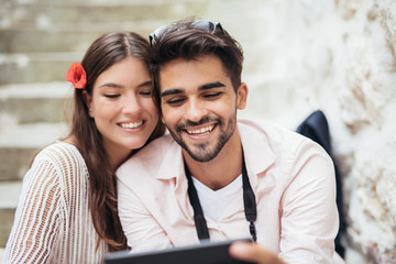 Obraz premium Romantic couple sitting on stairs and looking at tablet computer
