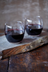 Two glasses of homemade red wine on wooden stand in kitchen