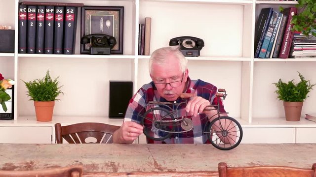 Senior man reparing shelf decoration, by table at home
