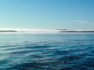 Obraz premium Wave of white fog over the blue lake in the morning
