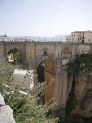 Old bridge connecting two parts of a city on mountains over a canyon with a waterfall in Ronda,...