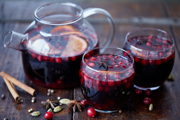 homemade mulled wine with cranberries in glasses and teapot on table in kitchen