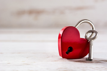 Red padlock hearts with key on white wooden background. Copyspace