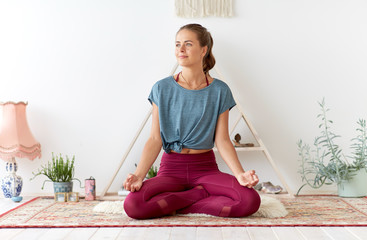 mindfulness, spirituality and healthy lifestyle concept - woman meditating in lotus pose at yoga...
