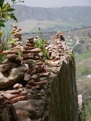 Fototapeta na wymiar Pile of orange stones in perfect balance on a cliff in the mountains of Ronda, Spain