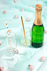Green bottle of champagne on turquoise fabric cloth texture. White background, copy space for your text