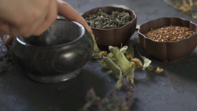 Preparation of medicinal herbs for use. Medicinal plants on the table. Woman rubs medicinal plants in a mortar
