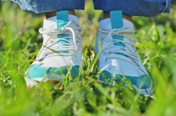A young girl standing on the green grass in sneakers