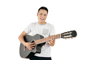 Portrait of young handsome Asian male musician playing the guitar and smiling at camera happily against white background