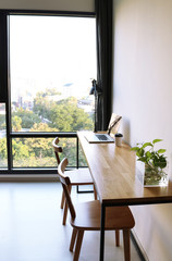 Wooden desktop with a laptop on it in a beautiful, modern penthouse with big windows