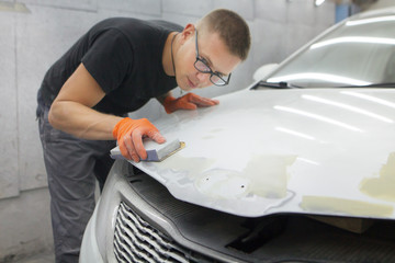 cute guy in black glasses with orange gloves displays the shape of the hood for the subsequent...