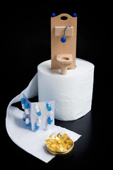 Wooden toy toilet, capsules and paper on black