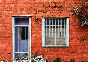 Fototapeta na wymiar Red wall with bar door and window with snow