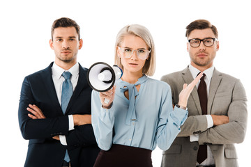dissatisfied businesswoman holding megaphone while colleagues standing with arms crossed isolated on white