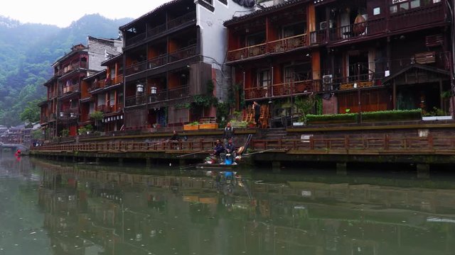 Boat cruise in the old Chinese town of Fenghuang in the Chinese mountains. Fenghuang is a county situated in the Hunan province. Point of view of ancient row boat rowing down the river
