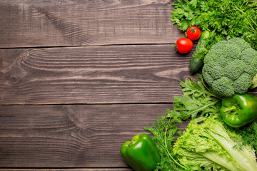Frame of green and red fresh vegetables on wooden background, top view