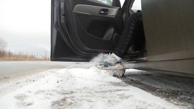 Winter Driving. A car standing on the road. Young man comes to the car and gets inside